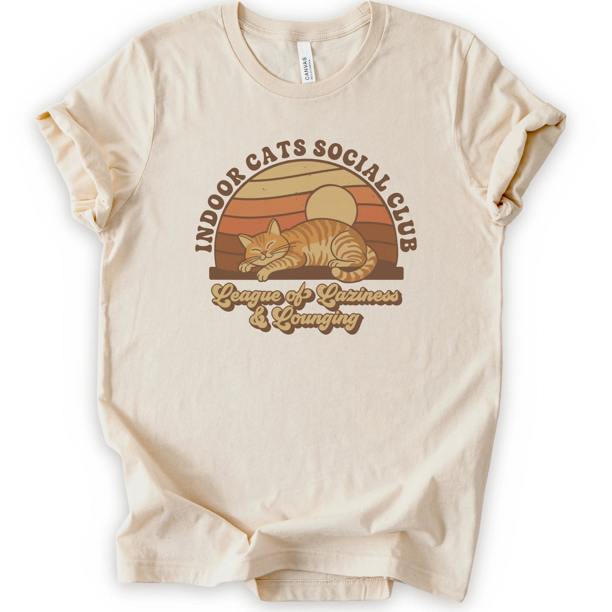 A natural short-sleeve crewneck t-shirt featuring a retro-style graphic of an orange tabby cat sleeping under a sunset, with the text 'INDOOR CATS SOCIAL CLUB' and 'League of Laziness & Lounging'.