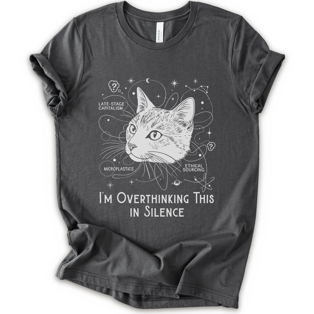 An asphalt short-sleeve crewneck t-shirt with a white graphic print of a cat's head surrounded by celestial and philosophical doodles, with the text 'I'M OVERTHINKING THIS IN SILENCE'.