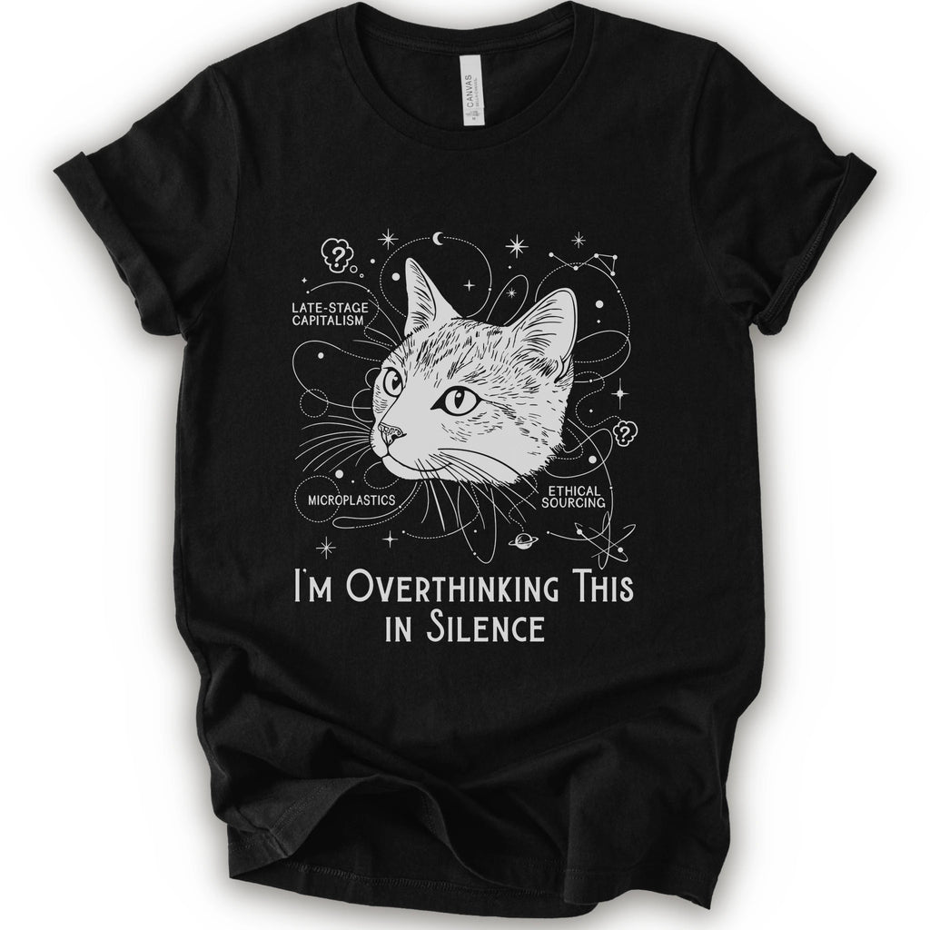 A black short-sleeve crewneck t-shirt with a white graphic print of a cat's head surrounded by celestial and philosophical doodles, with the text 'I'M OVERTHINKING THIS IN SILENCE'.