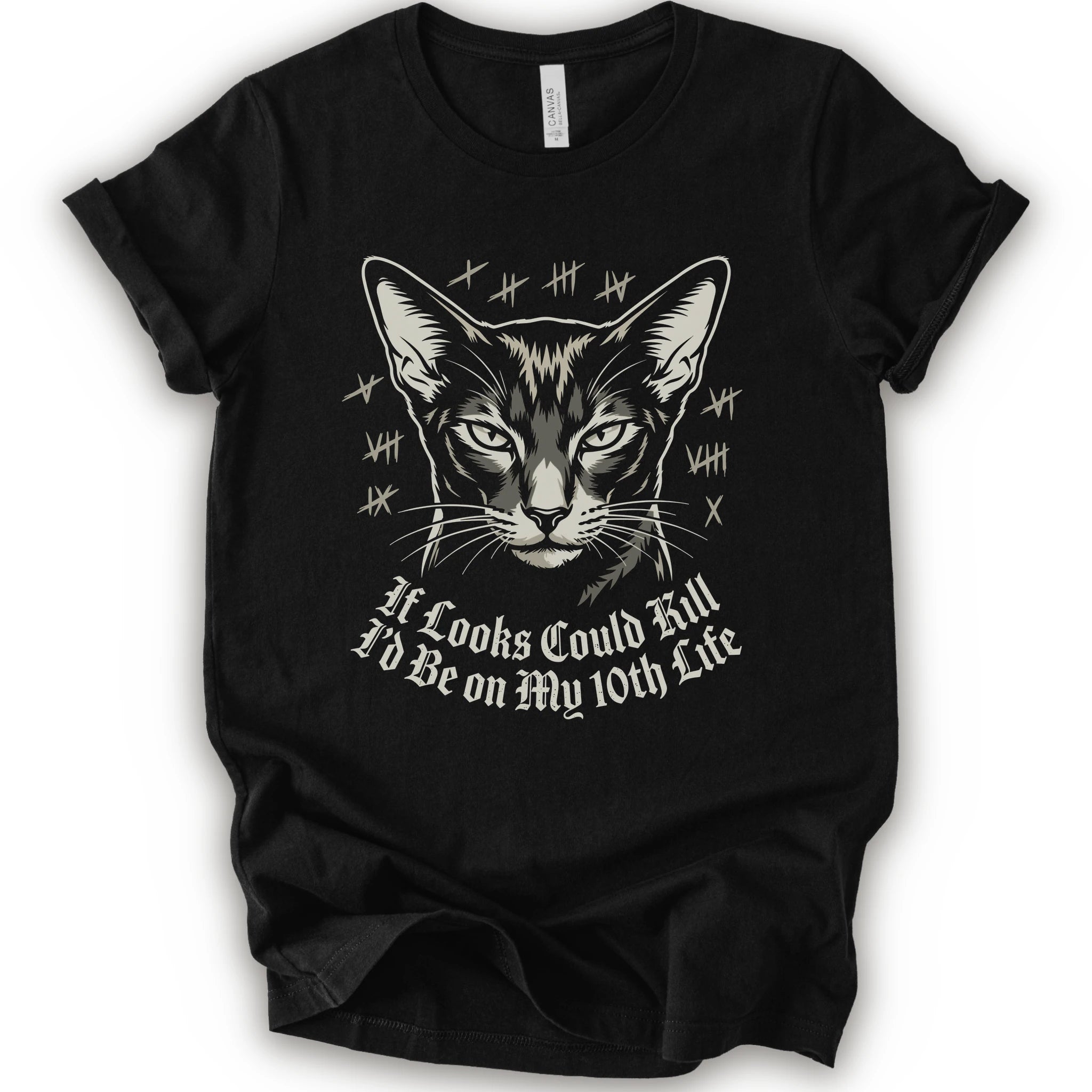 A black short-sleeve crewneck t-shirt featuring a graphic print of a cat's face with tally marks and the text 'It Looks Could Fill I'd Be on My 10th Life' in a white gothic font.