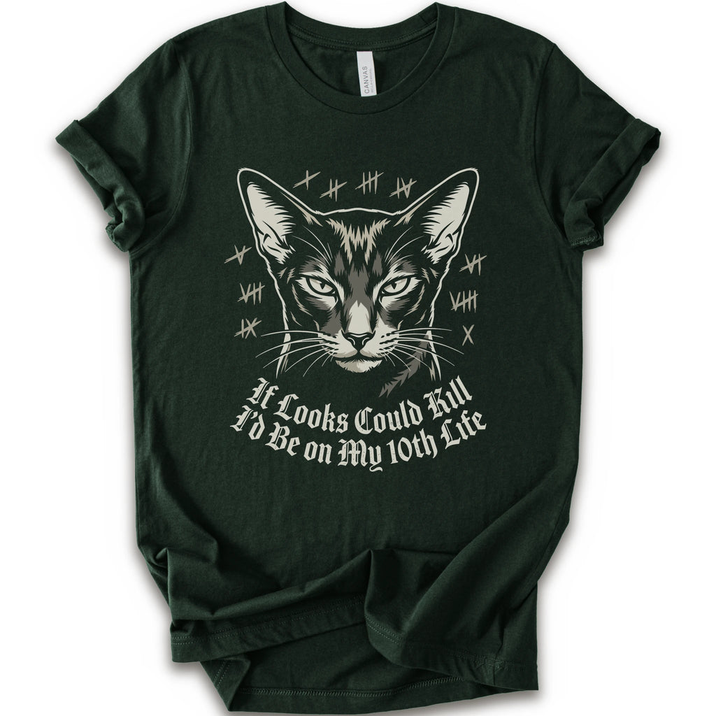 A forest short-sleeve crewneck t-shirt featuring a graphic print of a cat's face with tally marks and the text 'It Looks Could Fill I'd Be on My 10th Life' in a white gothic font.