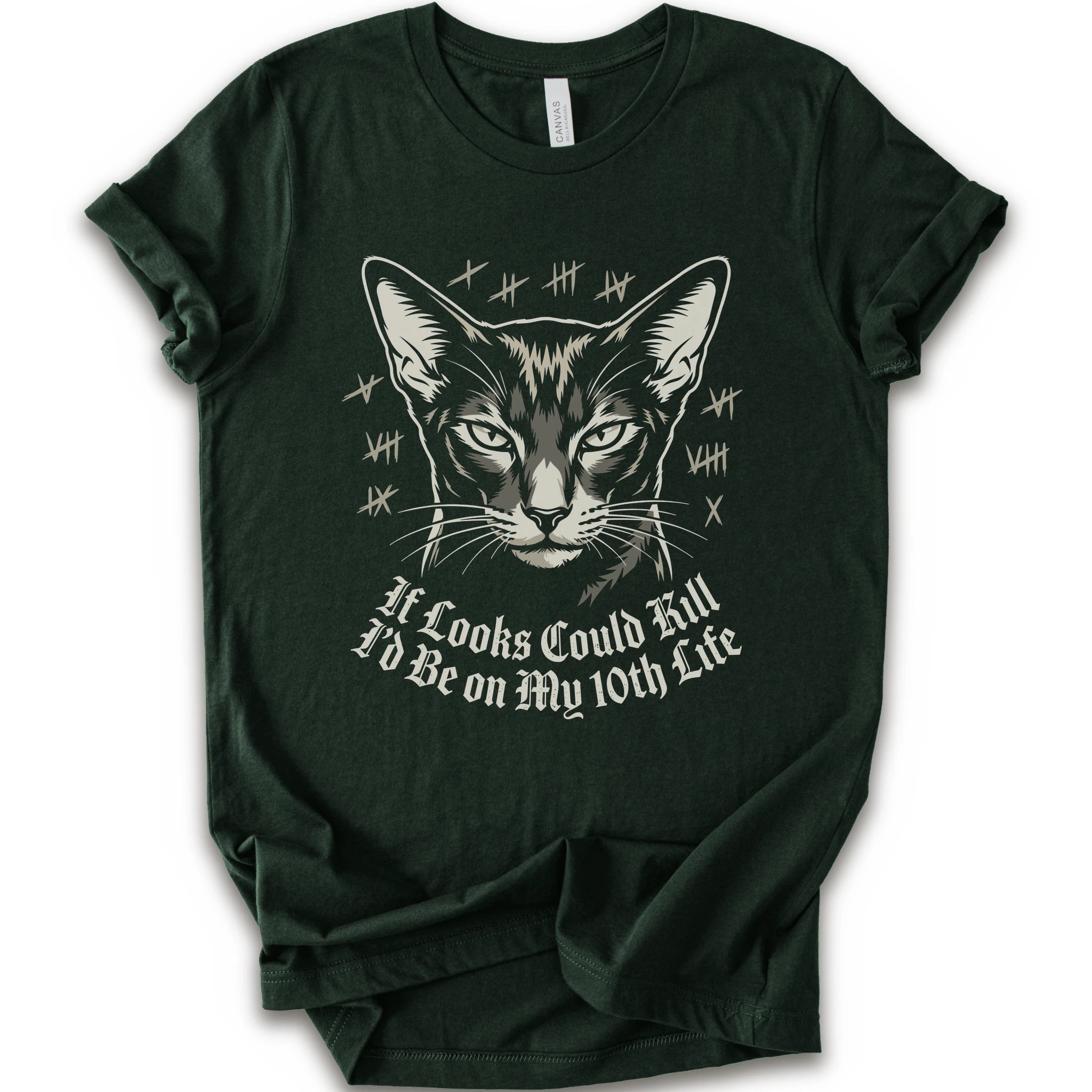 A forest short-sleeve crewneck t-shirt featuring a graphic print of a cat's face with tally marks and the text 'It Looks Could Fill I'd Be on My 10th Life' in a white gothic font.