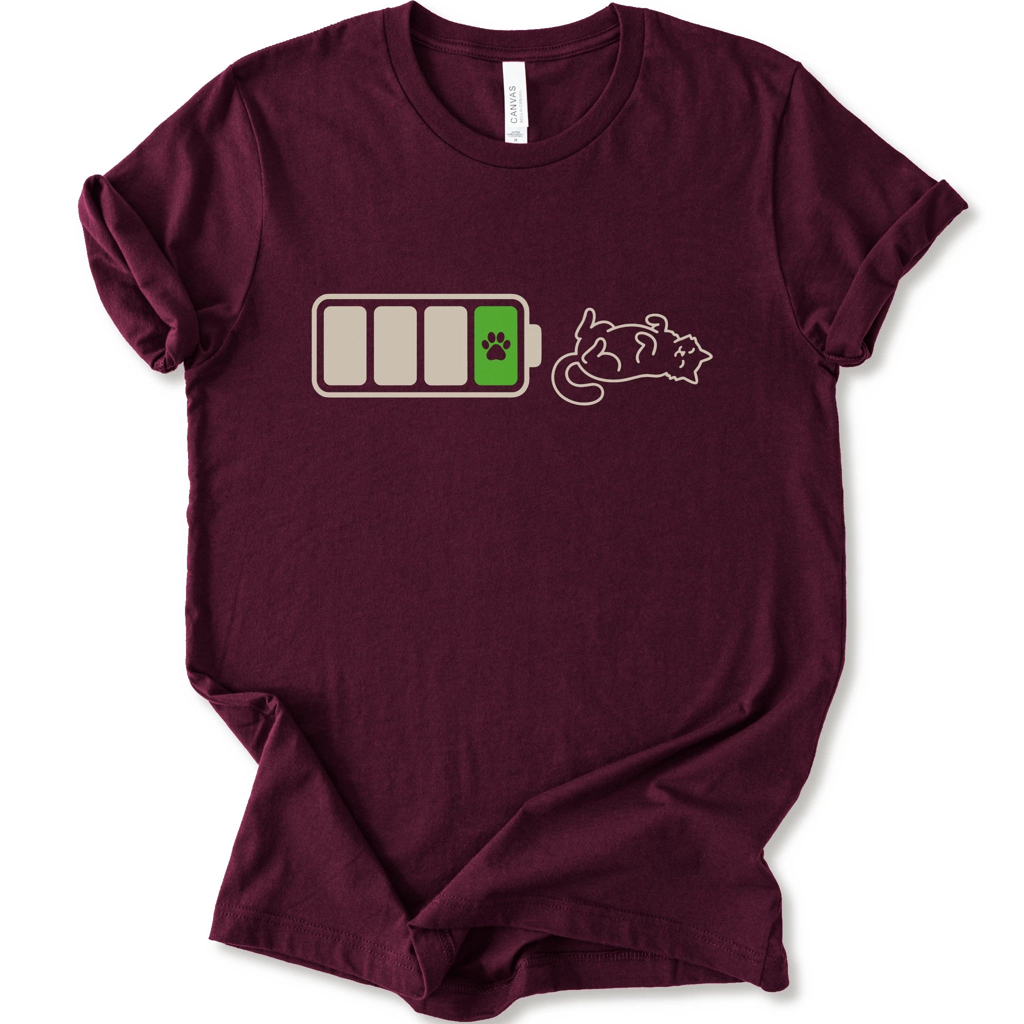 A maroon short-sleeve crewneck t-shirt featuring a graphic of a battery with three bars, a green battery cell with a black paw print, and a white line-art illustration of a sleeping cat.