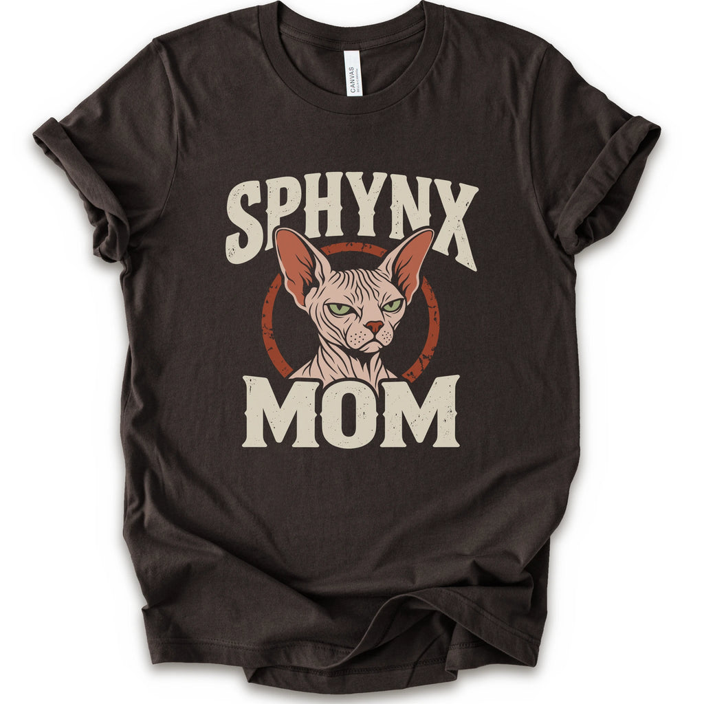 A brown short-sleeve crewneck t-shirt with a graphic print of a Sphynx cat and the text 'SPHYNX MOM' in distressed cream lettering.