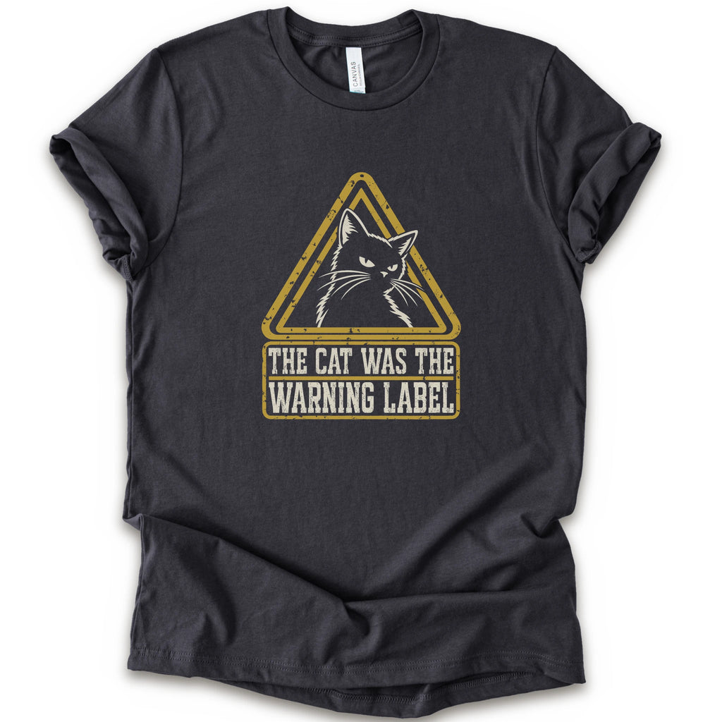 A dark grey short-sleeve crewneck t-shirt with a distressed yellow and white graphic on the front showing a cat inside a warning triangle and the text 'THE CAT WAS THE WARNING LABEL'.