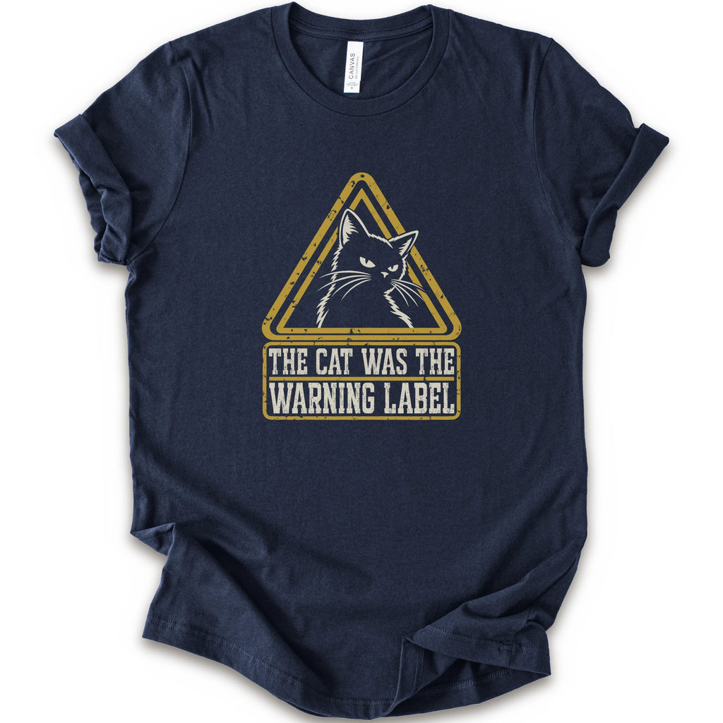 A navy short-sleeve crewneck t-shirt with a distressed yellow and white graphic on the front showing a cat inside a warning triangle and the text 'THE CAT WAS THE WARNING LABEL'.