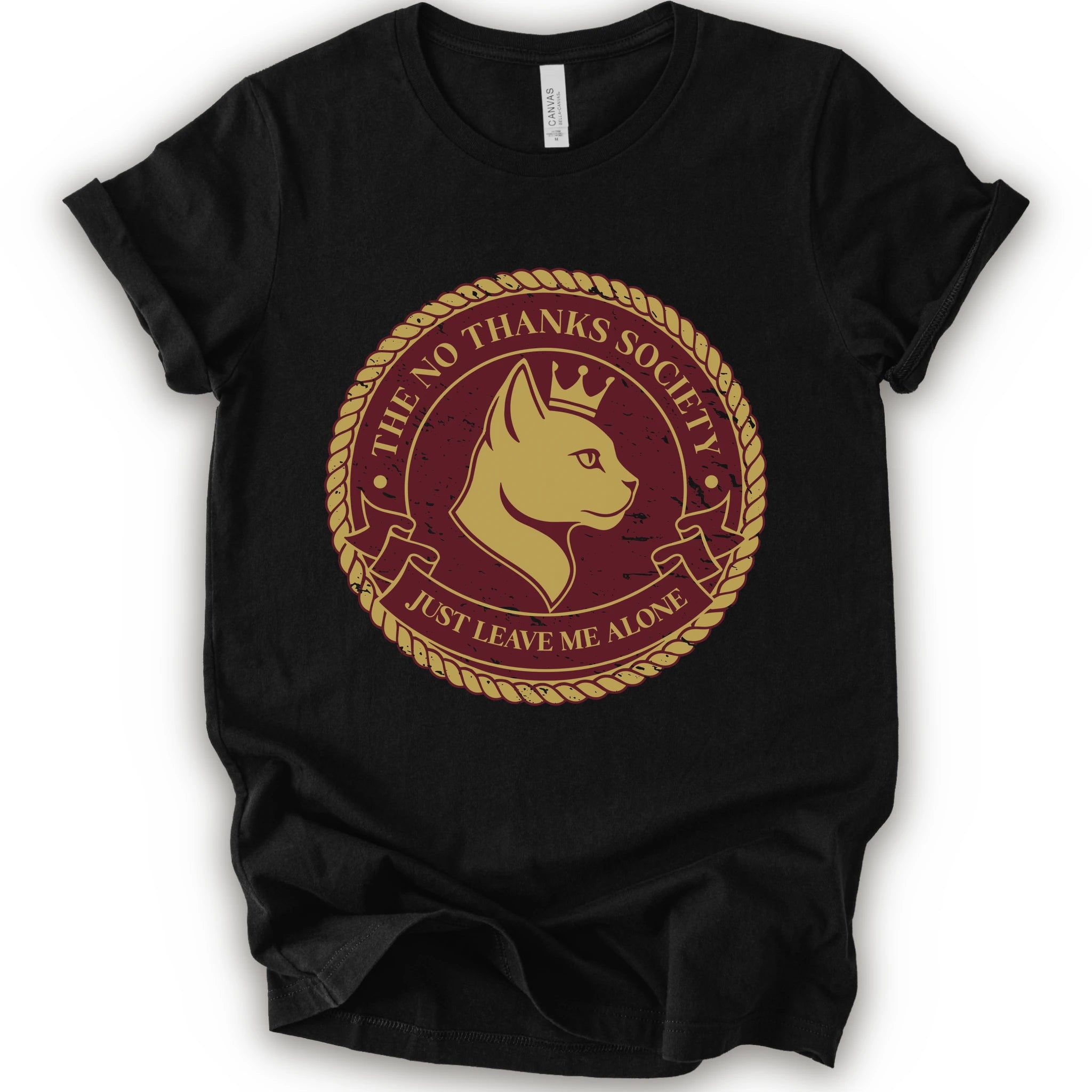A black short-sleeve t-shirt with a circular graphic print on the front. The graphic features a golden-yellow cat profile wearing a crown, surrounded by a rope border and the text 'THE NO THANKS SOCIETY' and 'JUST LEAVE ME ALONE' in a maroon background.