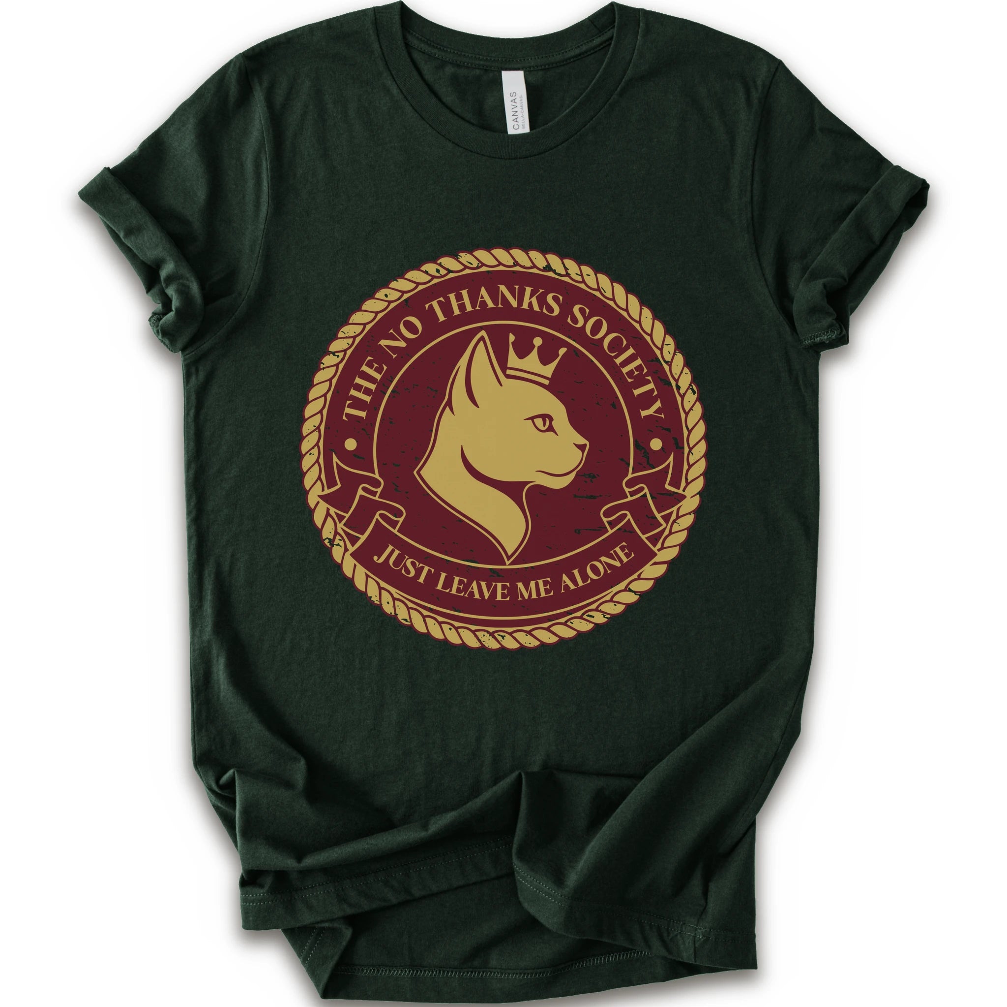 A forest short-sleeve t-shirt with a circular graphic print on the front. The graphic features a golden-yellow cat profile wearing a crown, surrounded by a rope border and the text 'THE NO THANKS SOCIETY' and 'JUST LEAVE ME ALONE' in a maroon background.