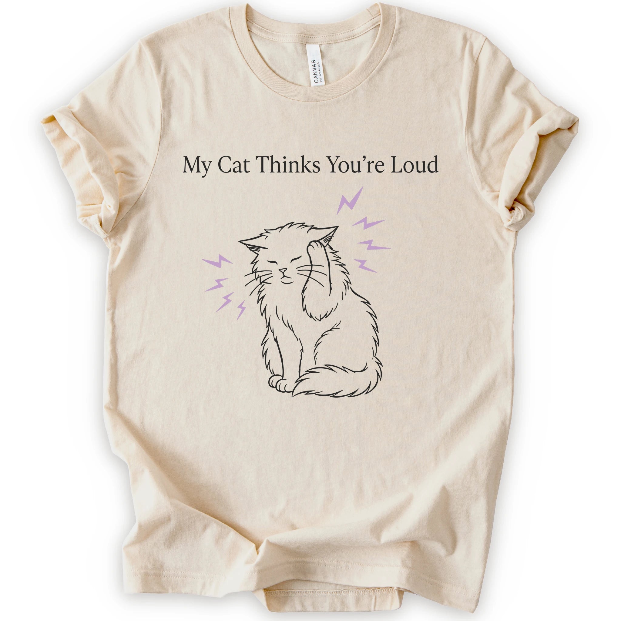 A natural short-sleeve t-shirt with a graphic print of a black line-art cat closing its ear, surrounded by purple lightning bolts, with the text 'My Cat Thinks You're Loud' printed above in white.