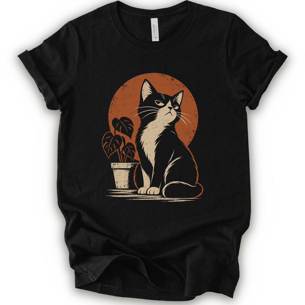 A black short-sleeve crewneck t-shirt with a retro-style graphic of a black and white cat sitting in front of an orange circular sun, next to a potted plant.