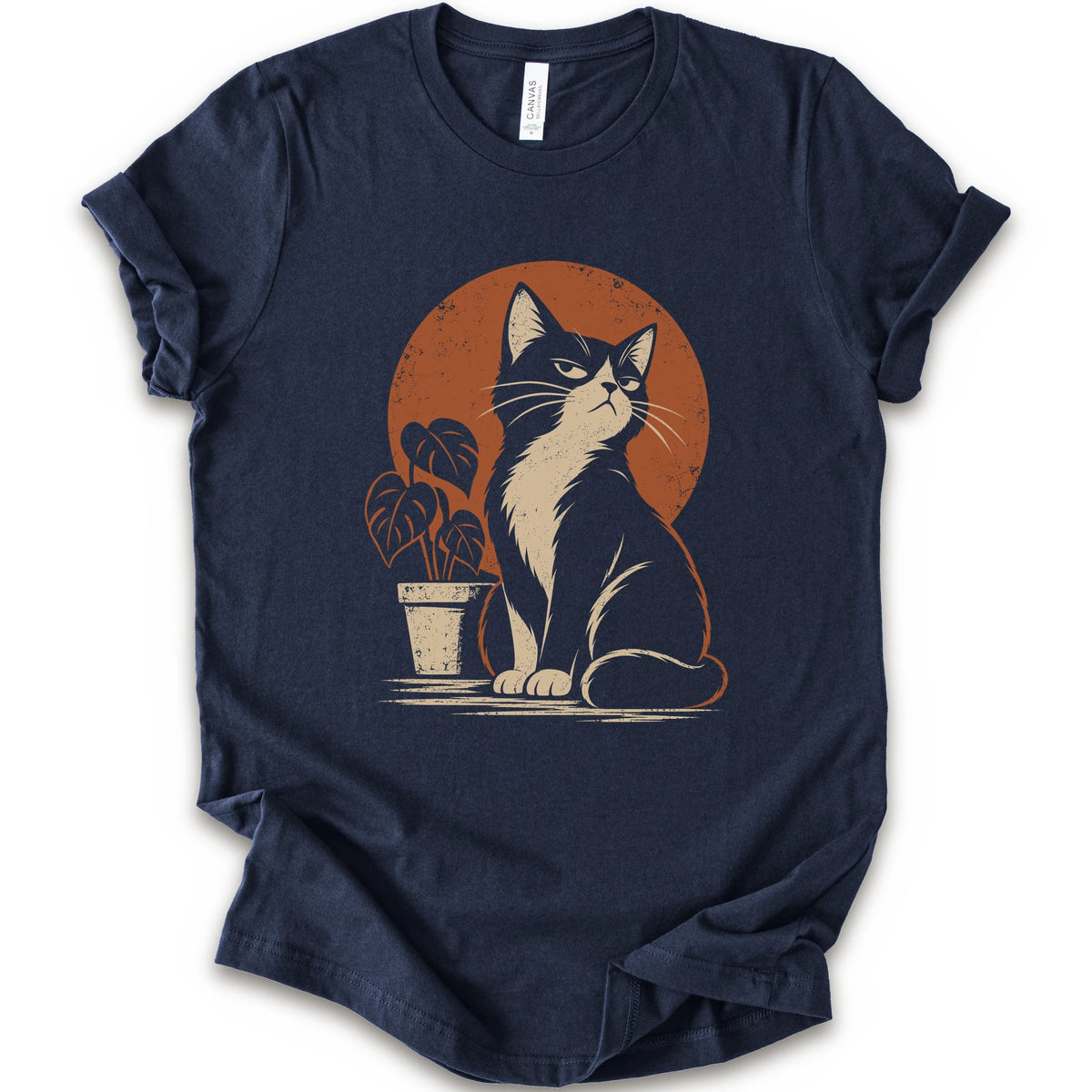 A navy short-sleeve crewneck t-shirt with a retro-style graphic of a black and white cat sitting in front of an orange circular sun, next to a potted plant.