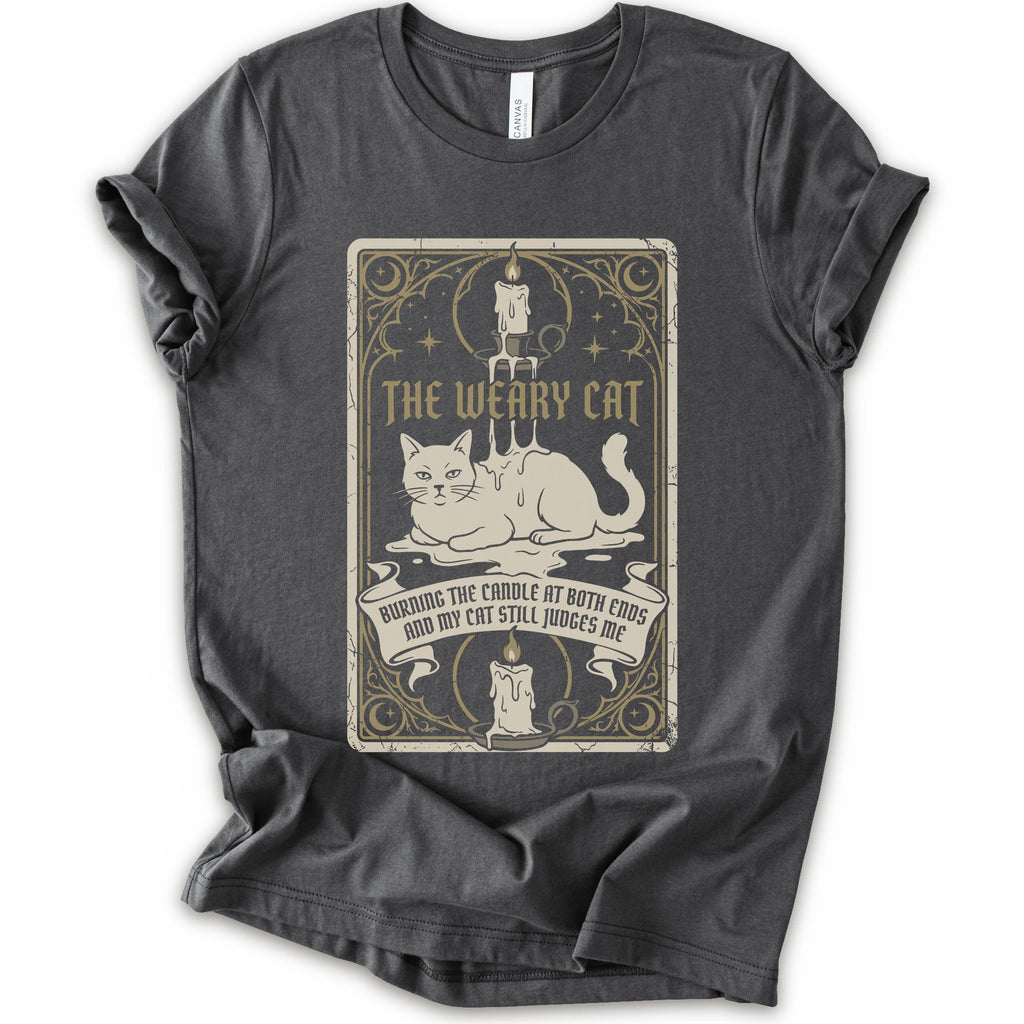 A asphalt short-sleeve crewneck t-shirt with a vintage-style graphic print on the front. The print features a white cat lying down inside a decorative frame with candles, stars, and the text 'THE WEARY CAT' and 'BURNING THE CANDLE AT BOTH ENDS AND MY CAT STILL JUDGES ME.
