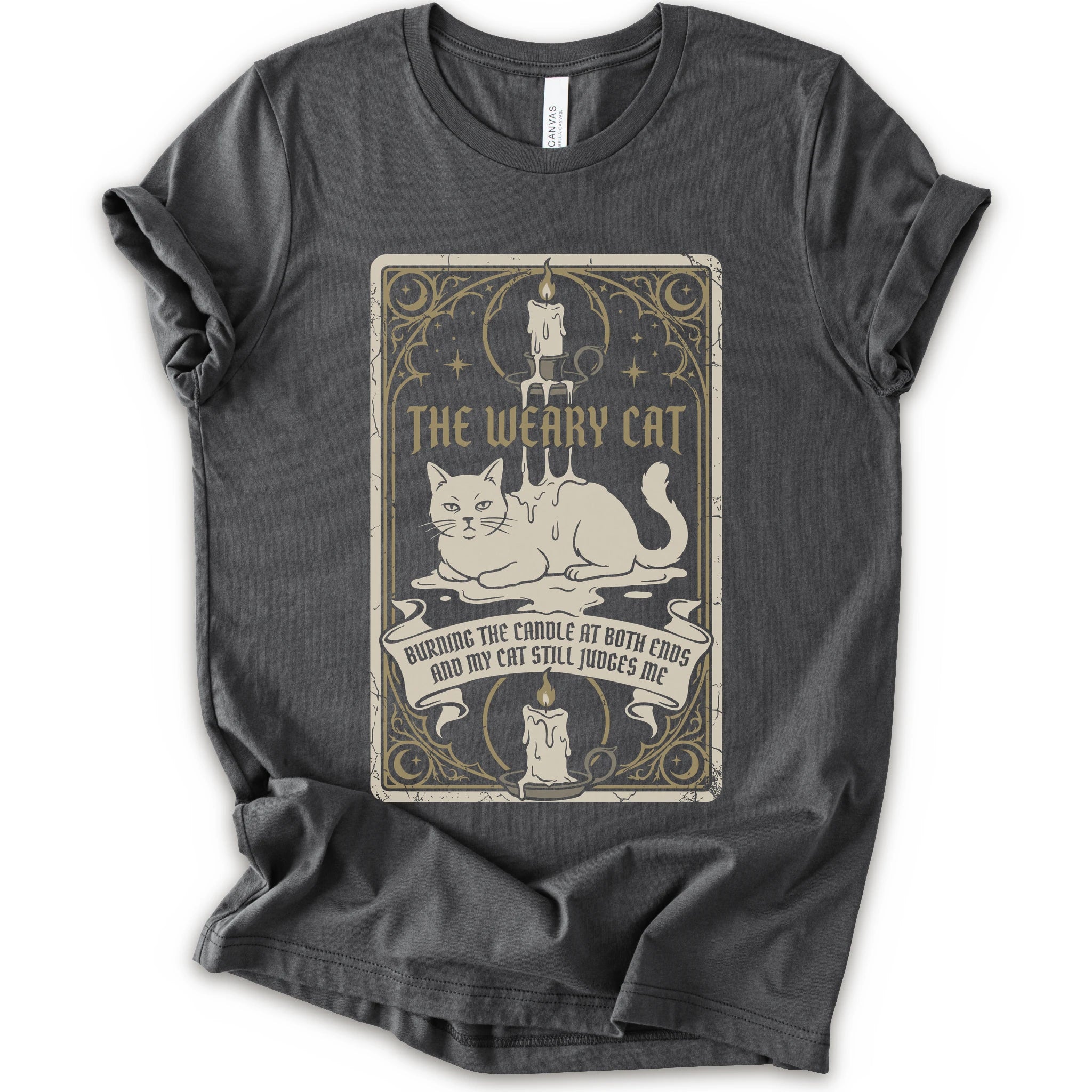 A asphalt short-sleeve crewneck t-shirt with a vintage-style graphic print on the front. The print features a white cat lying down inside a decorative frame with candles, stars, and the text 'THE WEARY CAT' and 'BURNING THE CANDLE AT BOTH ENDS AND MY CAT STILL JUDGES ME.