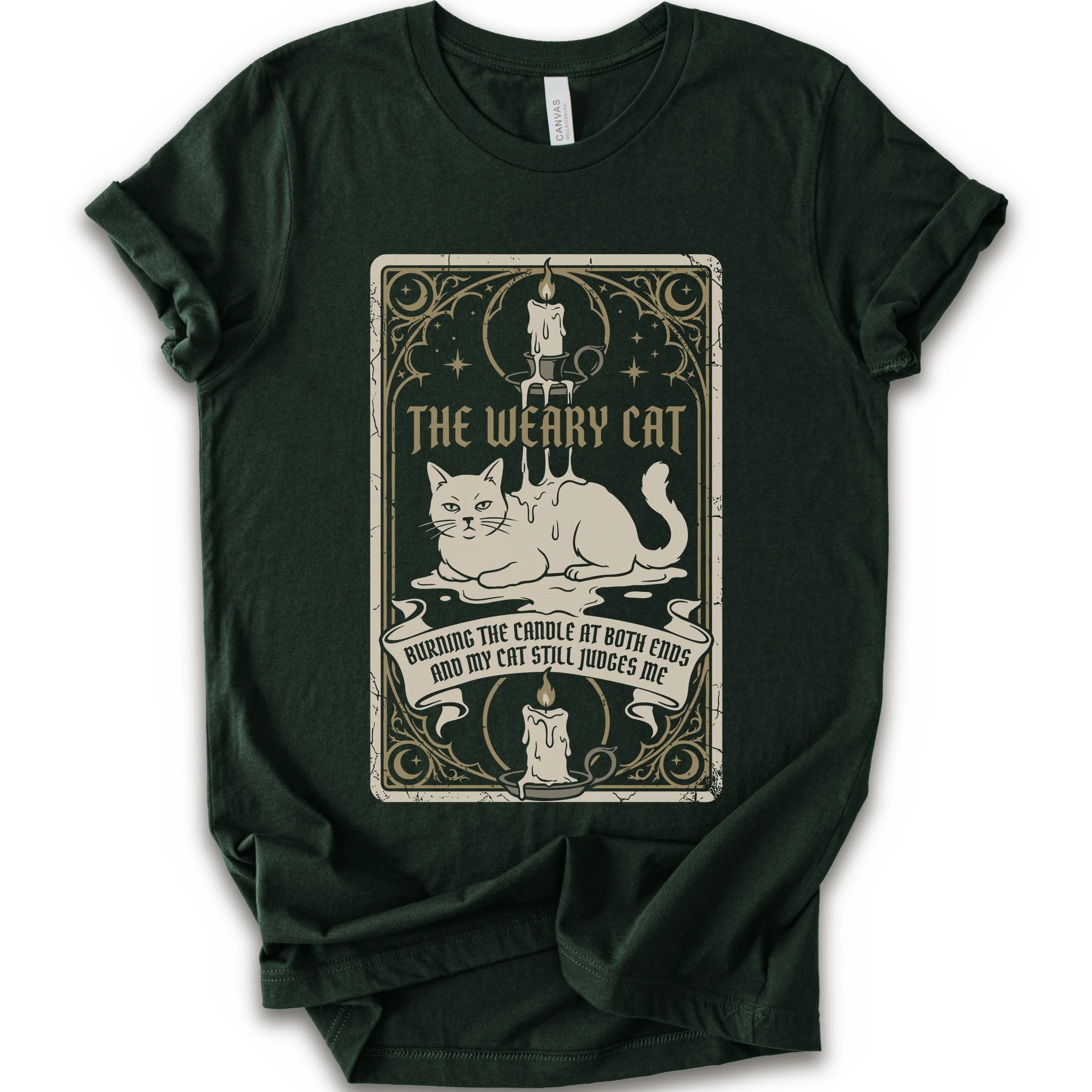 A forest short-sleeve crewneck t-shirt with a vintage-style graphic print on the front. The print features a white cat lying down inside a decorative frame with candles, stars, and the text 'THE WEARY CAT' and 'BURNING THE CANDLE AT BOTH ENDS AND MY CAT STILL JUDGES ME.