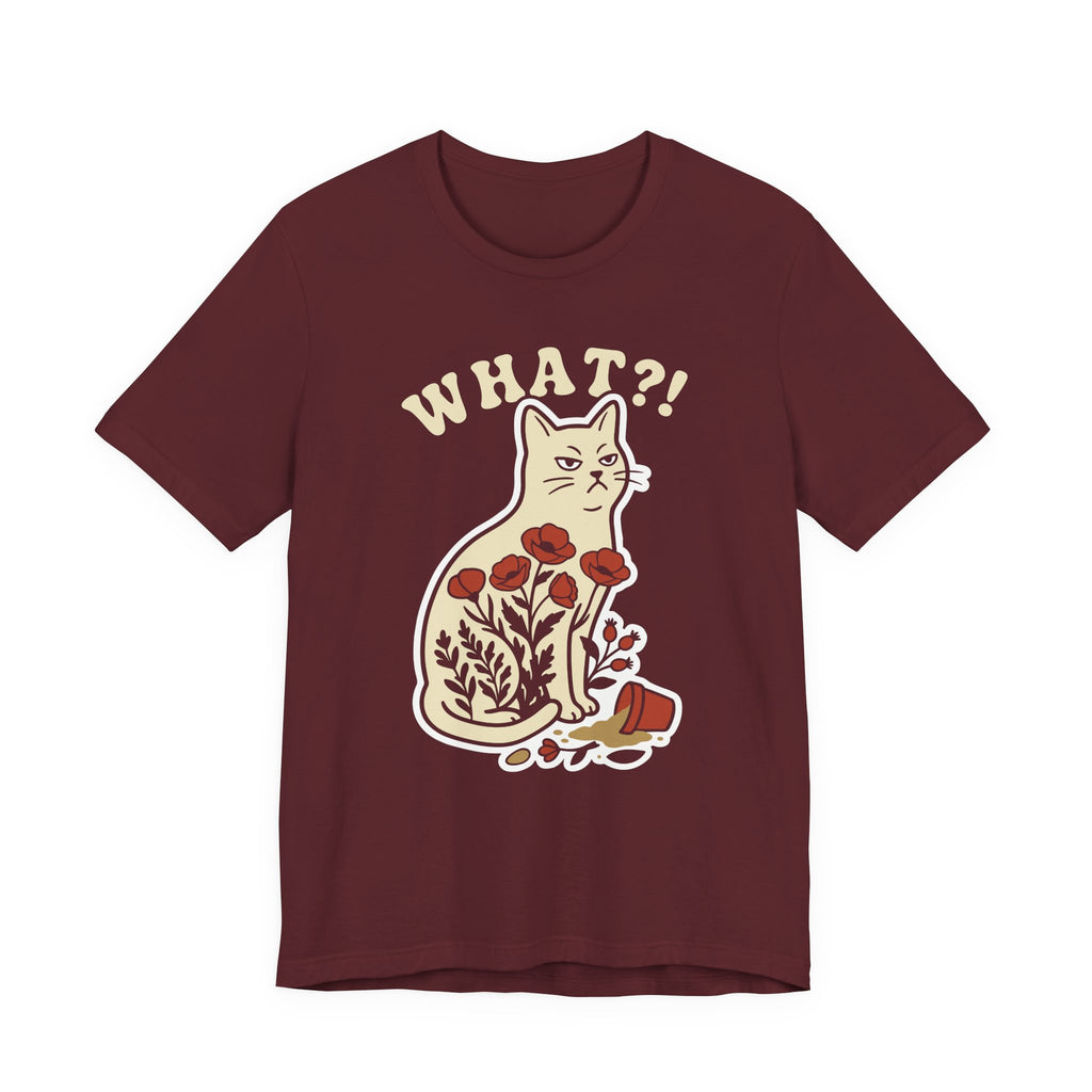 A maroon short-sleeve t-shirt with a graphic of a white cat sitting among red flowers, with the text 'WHAT?!' above it