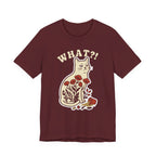 A maroon short-sleeve t-shirt with a graphic of a white cat sitting among red flowers, with the text 'WHAT?!' above it