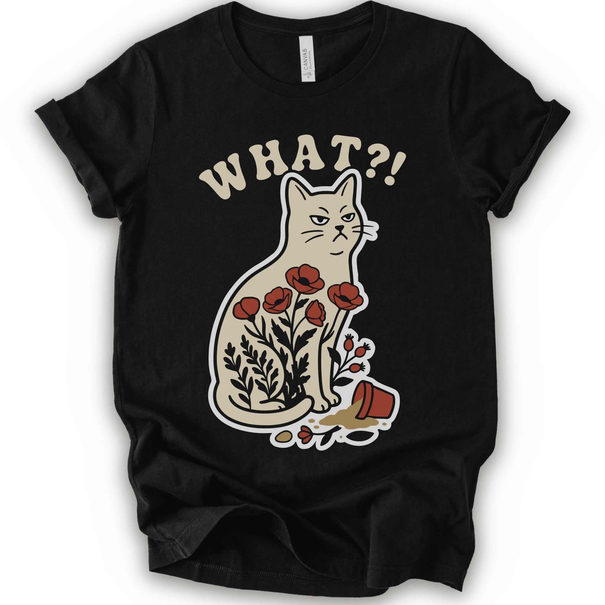Black graphic t-shirt with “WHAT?!” text above an unimpressed cream cat with red flowers beside a knocked-over plant pot