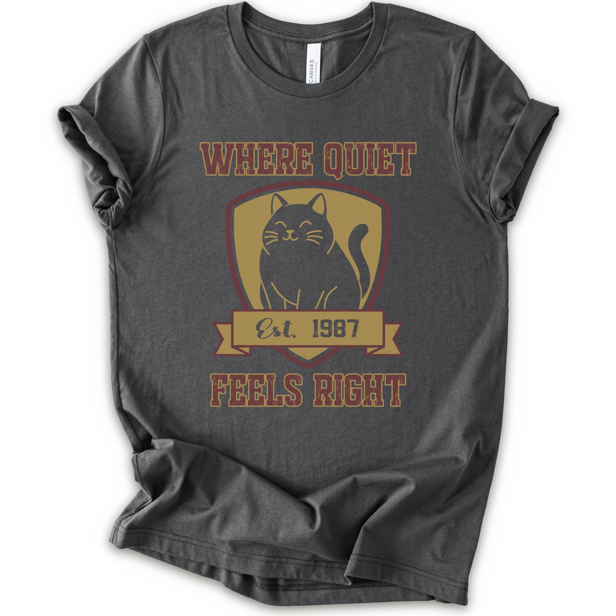 A asphalt short-sleeve t-shirt with a vintage-style graphic on the front featuring a black cat inside a gold shield and the text 'WHERE QUIET FEELS RIGHT Est. 1987'.