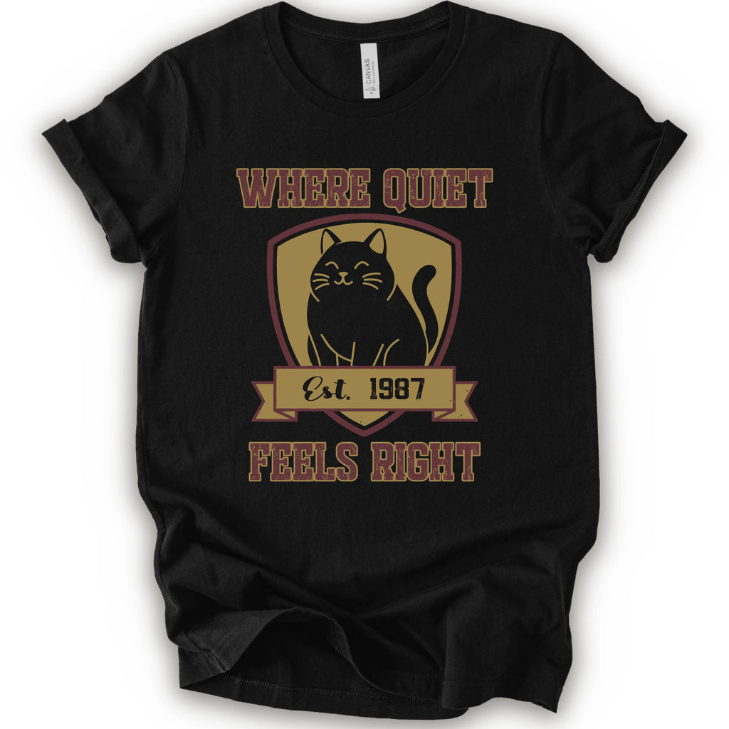 A black short-sleeve t-shirt with a vintage-style graphic on the front featuring a black cat inside a gold shield and the text 'WHERE QUIET FEELS RIGHT Est. 1987'.