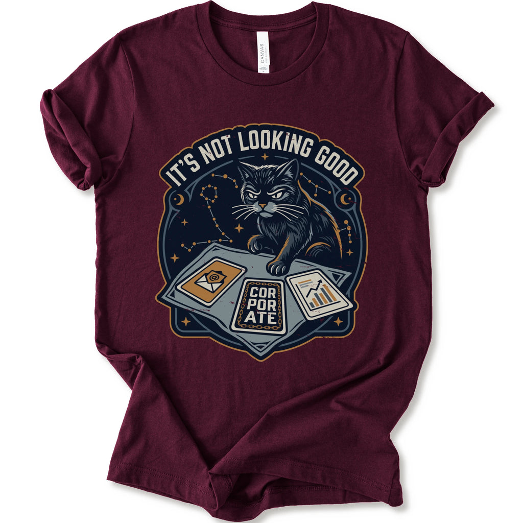 A maroon short-sleeve t-shirt with a graphic print of a black cat sitting on a laptop with the text 'IT'S NOT LOOKING GOOD' and 'CORPORATE'.