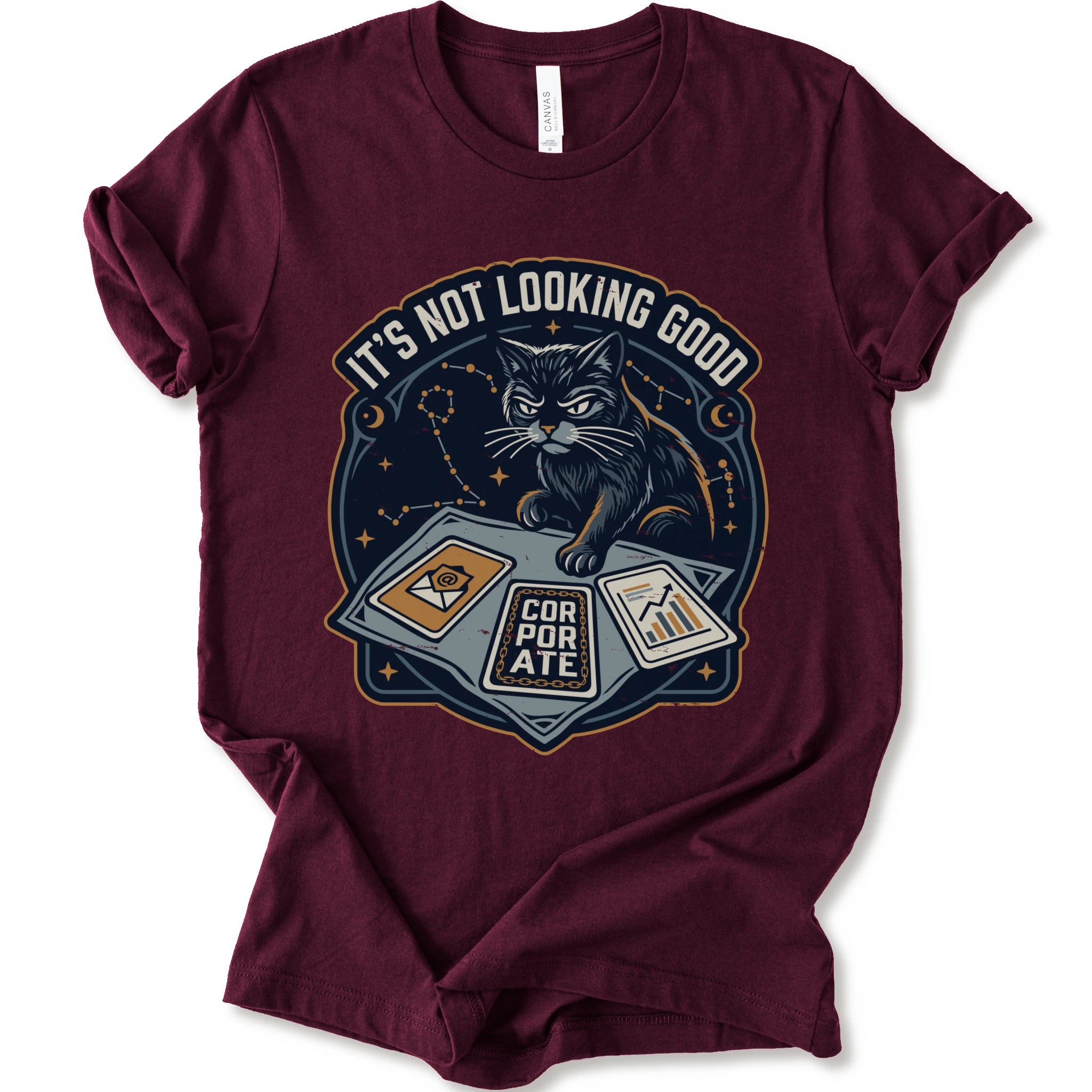 A maroon short-sleeve t-shirt with a graphic print of a black cat sitting on a laptop with the text 'IT'S NOT LOOKING GOOD' and 'CORPORATE'.