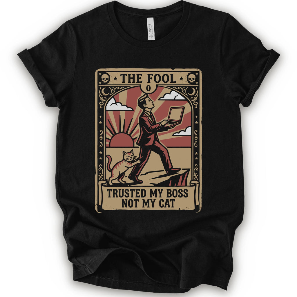 A black short-sleeve crewneck t-shirt with a vintage-style graphic print on the front. The graphic is styled like an old tarot card, featuring a man in a suit walking on a cliff while a cat watches, with the text 'THE FOOL' at the top and 'TRUSTED MY BOSS NOT MY CAT' at the bottom.