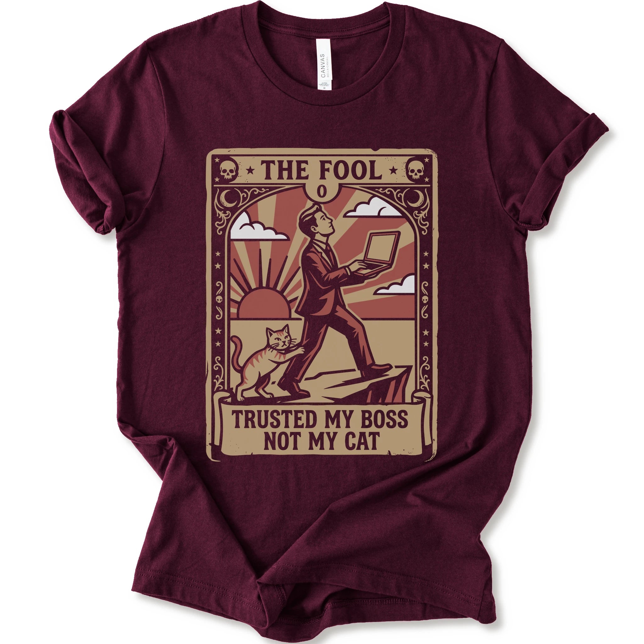 A maroon short-sleeve crewneck t-shirt with a vintage-style graphic print on the front. The graphic is styled like an old tarot card, featuring a man in a suit walking on a cliff while a cat watches, with the text 'THE FOOL' at the top and 'TRUSTED MY BOSS NOT MY CAT' at the bottom.