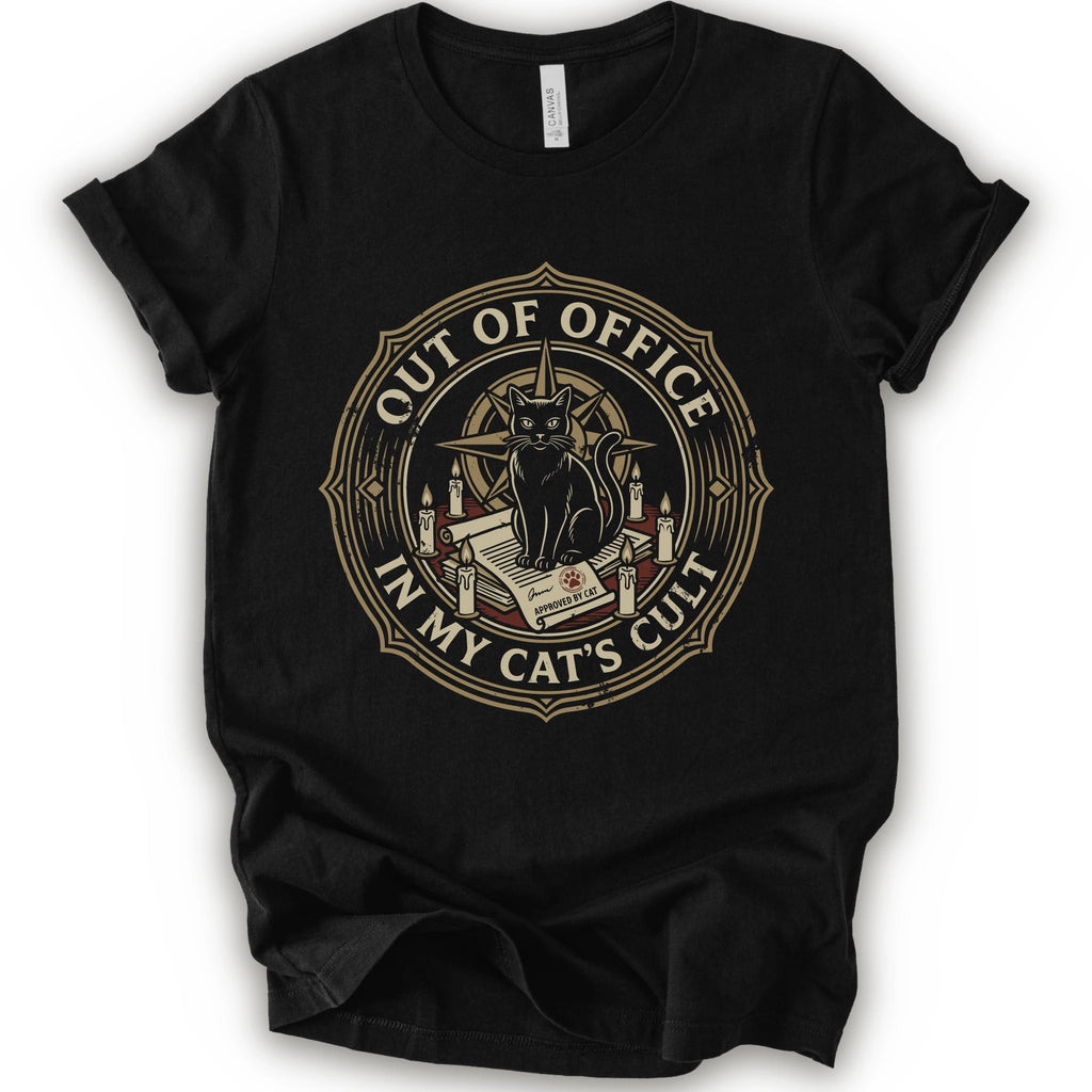 A black short-sleeve crewneck t-shirt with a circular graphic on the chest. The graphic features a black cat sitting on an open book surrounded by candles, with the text 'OUT OF OFFICE' and 'IN MY CAT'S CULT' in a vintage serif font.