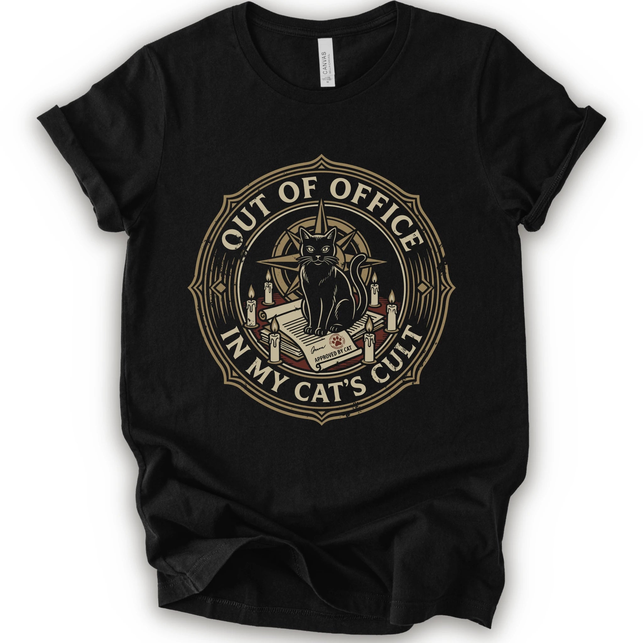 A black short-sleeve crewneck t-shirt with a circular graphic on the chest. The graphic features a black cat sitting on an open book surrounded by candles, with the text 'OUT OF OFFICE' and 'IN MY CAT'S CULT' in a vintage serif font.