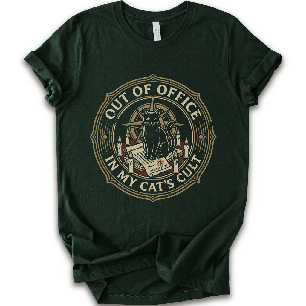 A forest short-sleeve crewneck t-shirt with a circular graphic on the chest. The graphic features a black cat sitting on an open book surrounded by candles, with the text 'OUT OF OFFICE' and 'IN MY CAT'S CULT' in a vintage serif font.