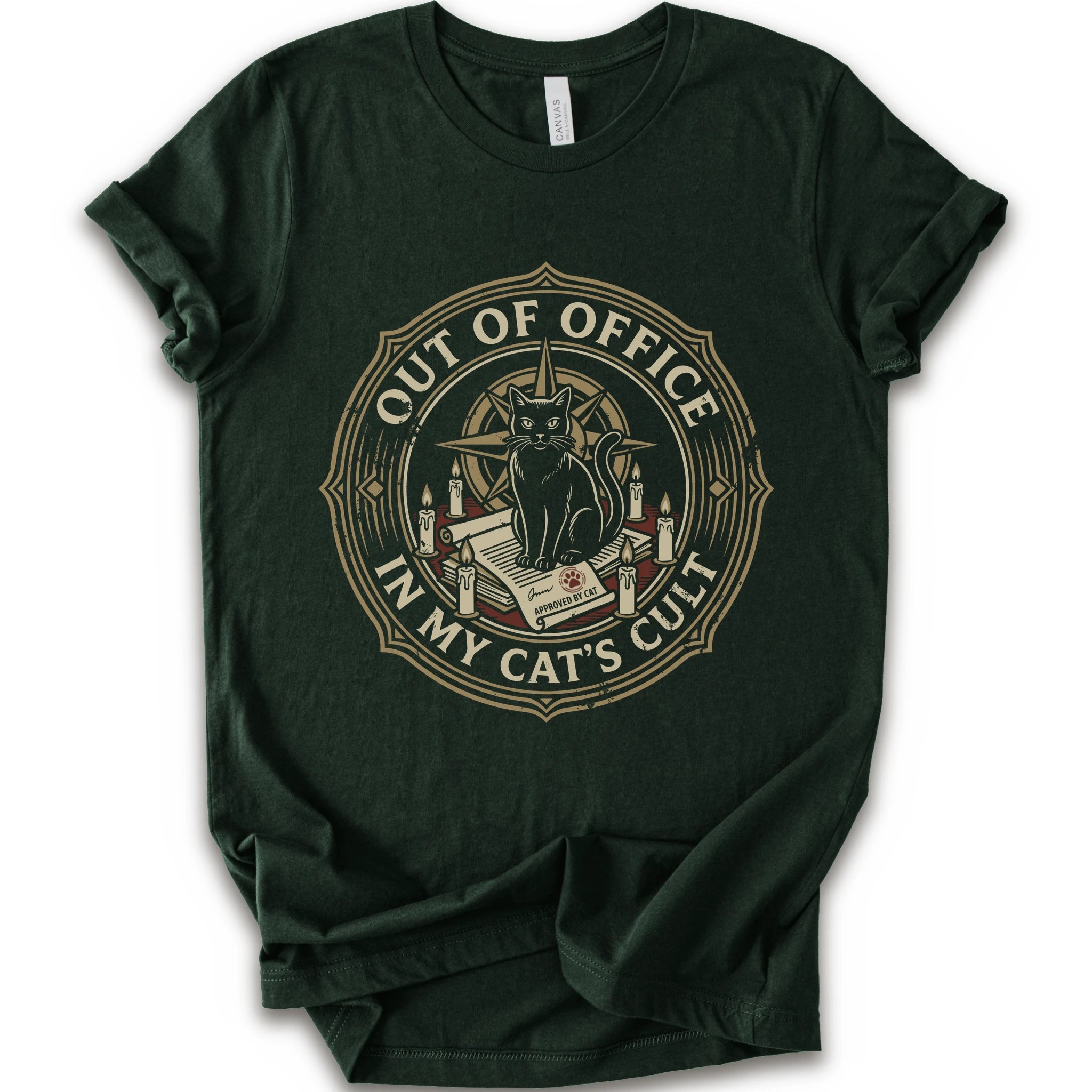A forest short-sleeve crewneck t-shirt with a circular graphic on the chest. The graphic features a black cat sitting on an open book surrounded by candles, with the text 'OUT OF OFFICE' and 'IN MY CAT'S CULT' in a vintage serif font.