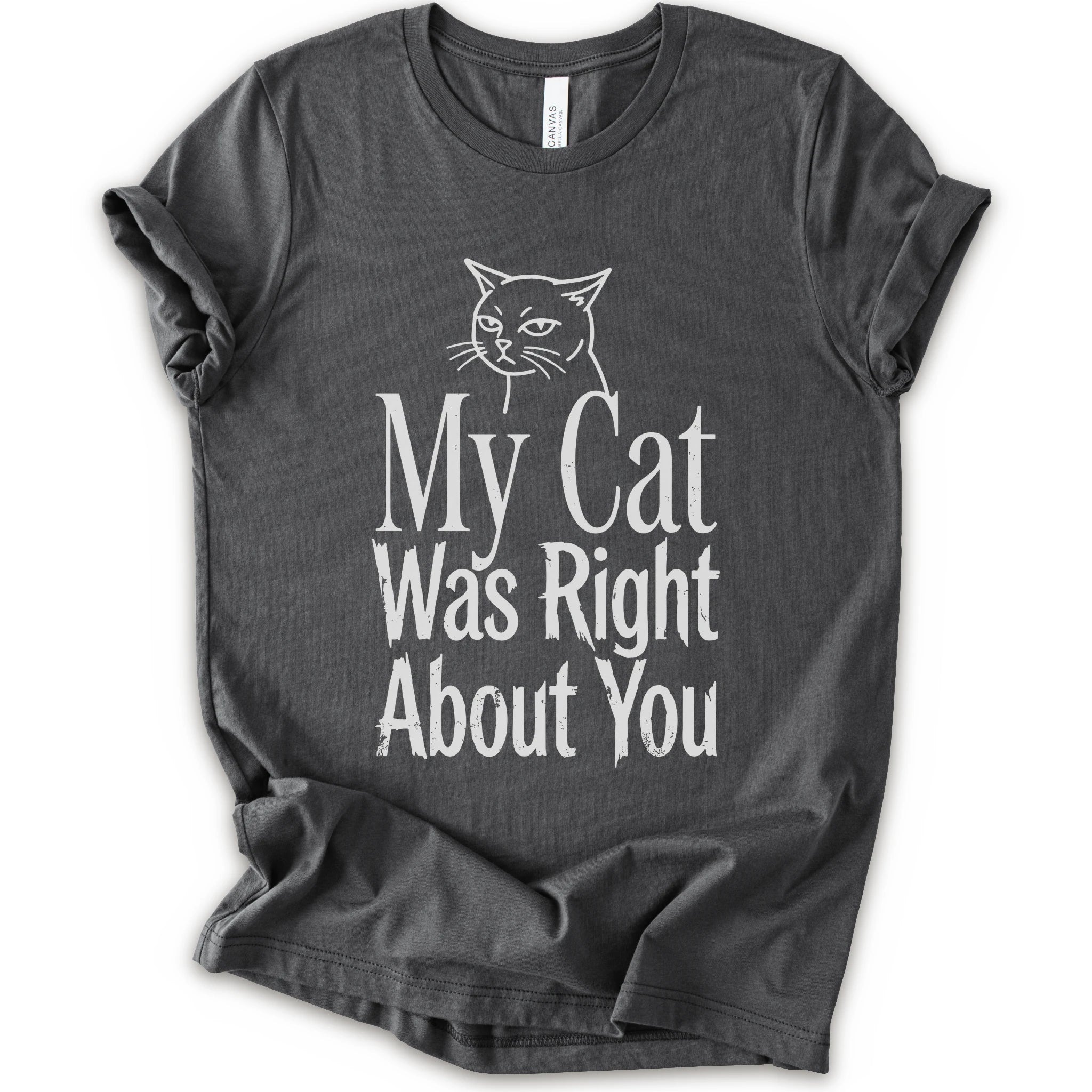 A asphalt short-sleeve crewneck T-shirt with a cat rendered in white outline sits above the text “My Cat Was Right About You,” arranged in oversized mixed serif and distressed lettering.