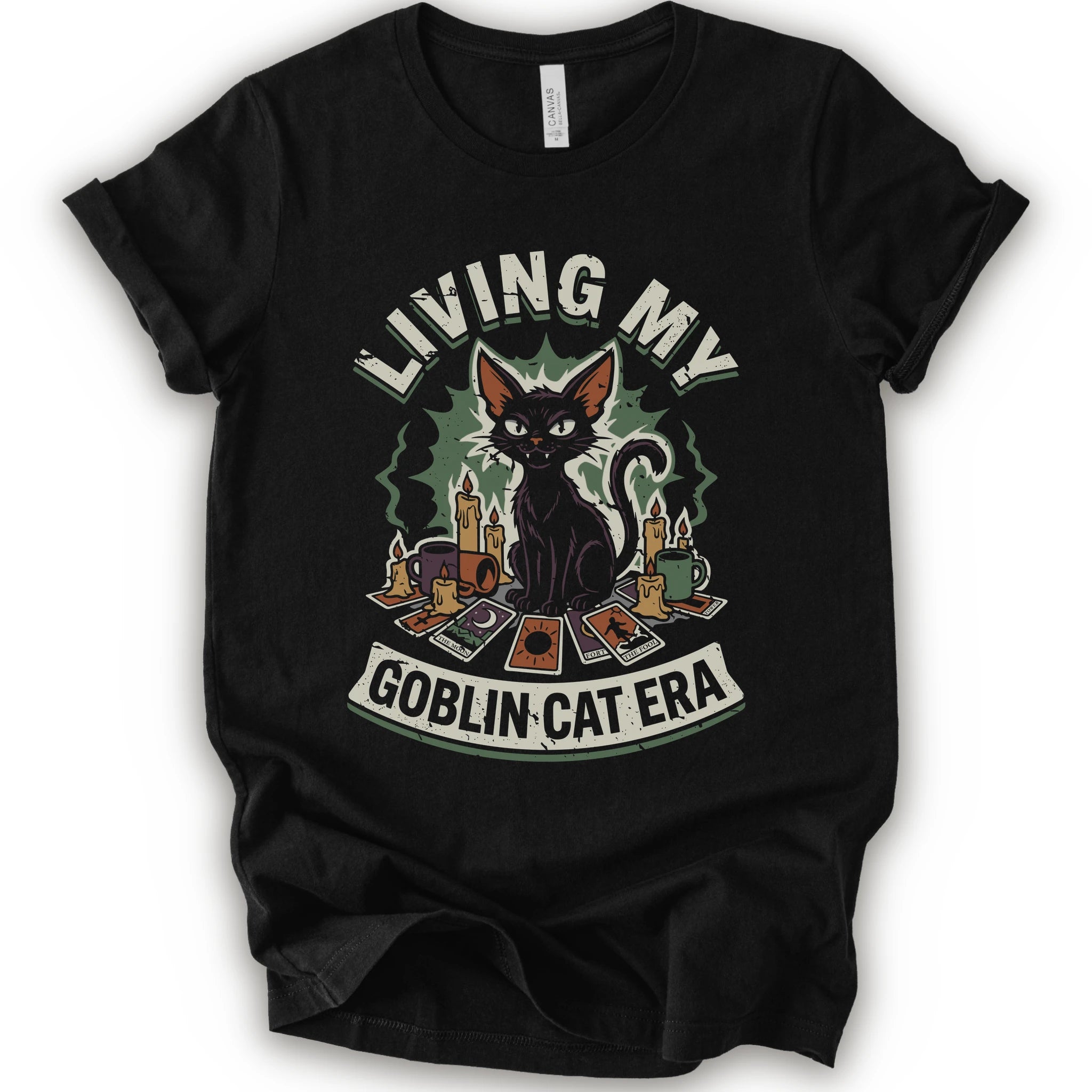 A black short-sleeve t-shirt with a graphic print of a black cat surrounded by candles, cards, and the text 'LIVING MY GOBLIN CAT ERA' in a distressed vintage style.