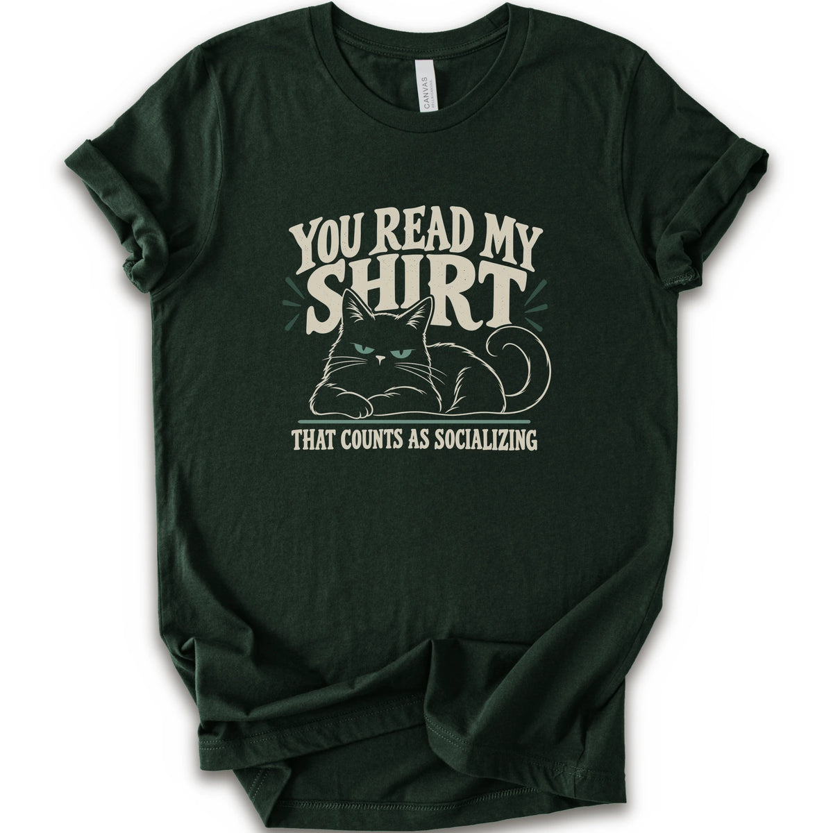 A forest short-sleeve crewneck t-shirt with a graphic print of a grumpy cat and the text 'YOU READ MY SHIRT THAT COUNTS AS SOCIALIZING' in cream and light green.